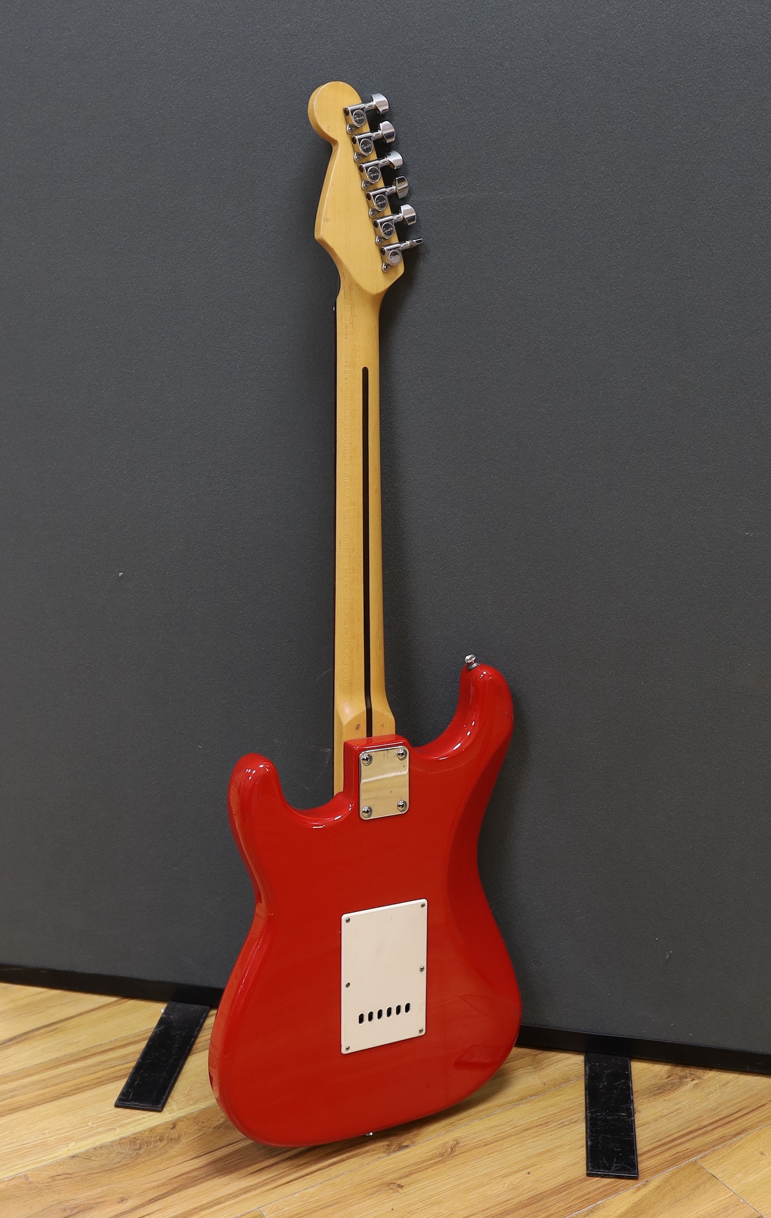 A Squier Strat by Fender electric guitar with rosewood neck and red lacquer body